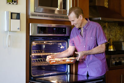 Senior man putting a casserole into the oven