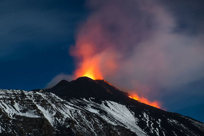 Scenic view of active volcano against sky at dusk