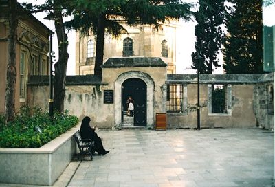 Side view of woman sitting on seat in city