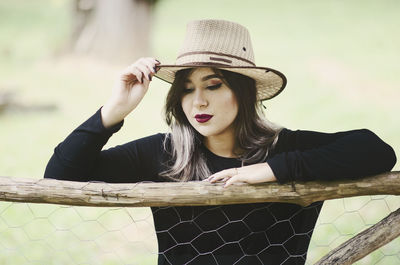 Young woman wearing hat standing by bamboo