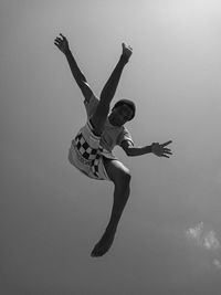 Low angle view of a boy jumping against the sky