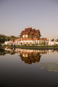 Reflection of buildings in lake against clear sky