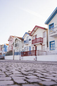 Houses by street against sky in city during winter