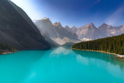 Scenic view of lake by mountains against blue sky