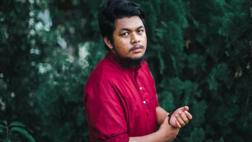 Portrait of young man standing against trees