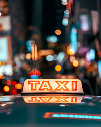 Close-up of illuminated taxi signbox with bokeh of city night