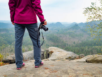 Woman on cliff. nature photographer hand holds mirror camera on peak of rock. dreamy autumn