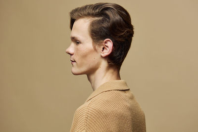 Side view of young woman looking away against pink background