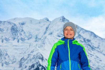 Portrait of young woman standing on snowcapped mountain