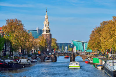 Boats in river amidst buildings in city against sky