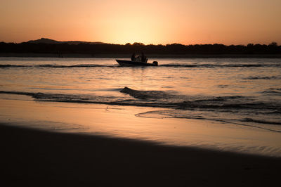 People in boat on sea against orange sky during sunset