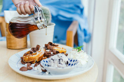 Cropped hand pouring honey from jar in plate