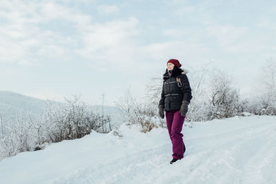 Full length of woman standing on snow against sky