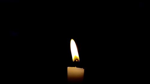 Close-up of lit candle in dark room