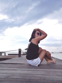 Young woman by sea against sky