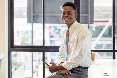 Happy young african business man student professional user hold smartphone online sit at home office 