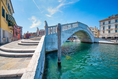 Arch bridge over canal by buildings in city