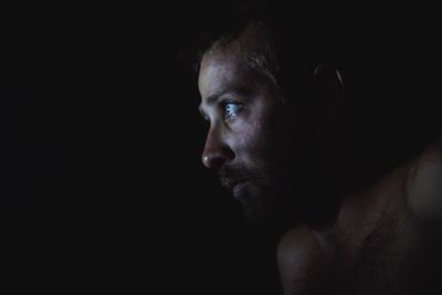 Portrait of young man against black background