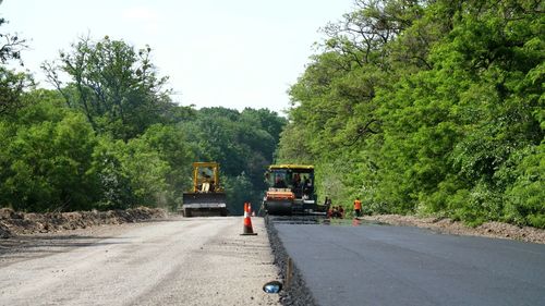 Roller compactor machine and asphalt finisher laying a new fresh asphalt pavement
