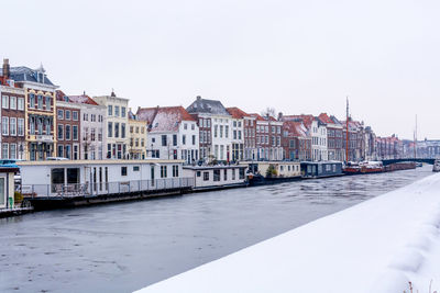 Buildings by river against clear sky in city