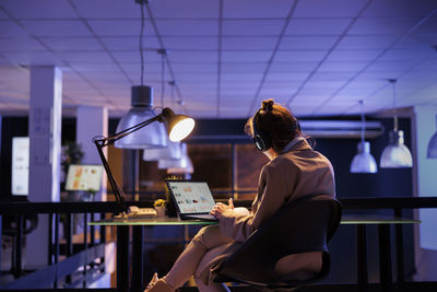 Rear view of woman using laptop while sitting in cafe