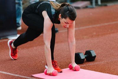 Young woman exercising with dumbbells on sports track