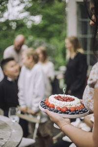 Woman holding fresh fruit cake at birthday celebration