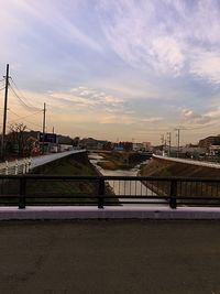 Bridge over river by buildings against sky during sunset