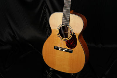 High angle view of acoustic guitar on bed