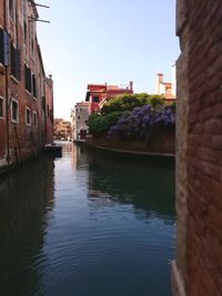 Canal by buildings against sky