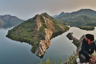 Man standing on mountain by lake against clear sky