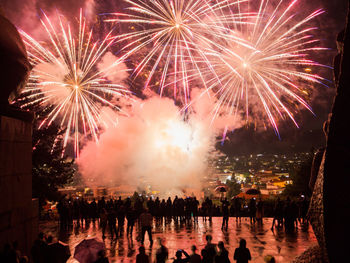 People watching firework display over city at night