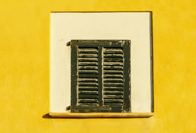 Close-up of window on yellow wall