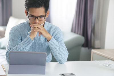 Midsection of man using mobile phone while sitting on table