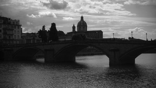 Arch bridge over river against buildings in city