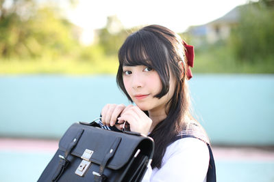 Portrait of woman holding bag outdoors