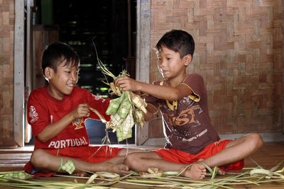 Happy friends sitting with arms raised