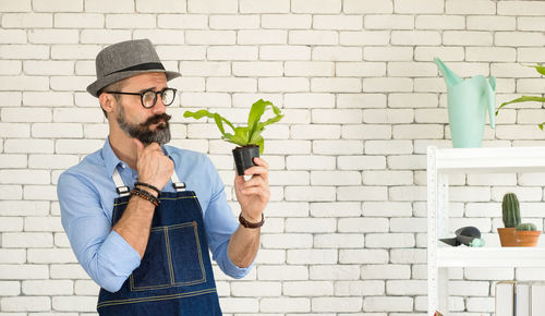 Man wearing hat standing against wall