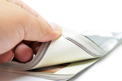 Close-up of hand holding book on white background