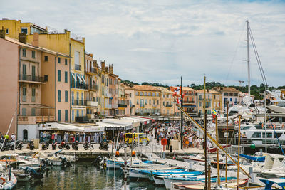 Boats moored on sea at marina grande against cloudy sky