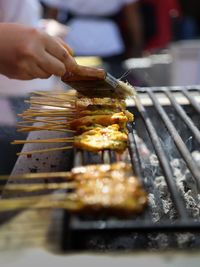 Close-up of person preparing food on barbecue grill