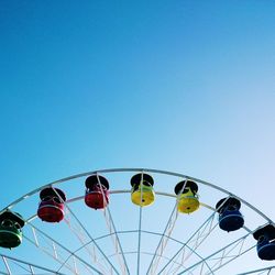 Low angle view of ferris wheel against clear blue sky