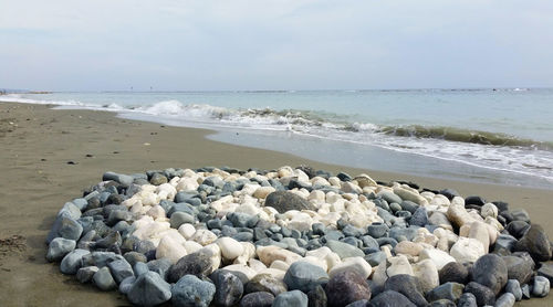 Stones at beach against sky