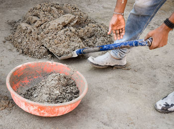 High angle view of person working at construction site. he is gathering cement mixture in a basket.