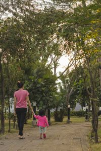 Rear view of women walking along trees