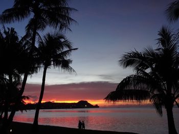 Silhouette palm trees on beach against sky during sunset