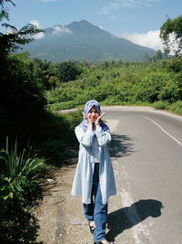 Young woman standing on road against mountain