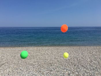 Balloons on beach against blue sky