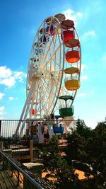 Low angle view of ferris wheel against blue sky