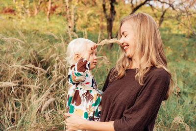 Rear view of mother holding daughter outdoors